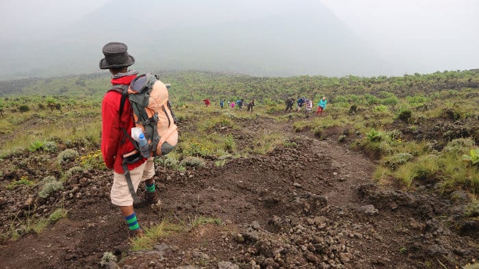 A local guide awaits tourists as they slowly make their way up the slopes of Mount Nyiragongo