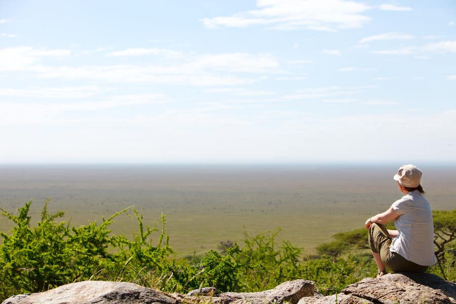 Woman watches over the Serengeti plains, filled with wildlife
