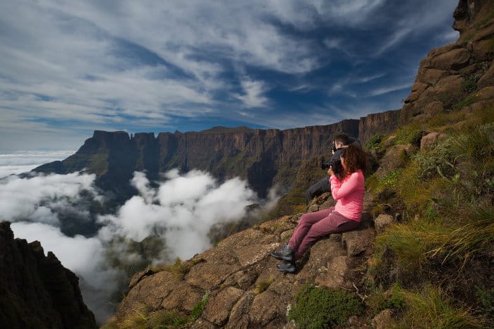 Two hikers take pictures of the Drakensberg Amphitheatre from Witches Viewpoint