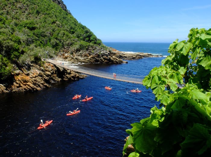 Kayaks pass under the Storms River Mouth suspension bridge in Tsitsikamma National Park