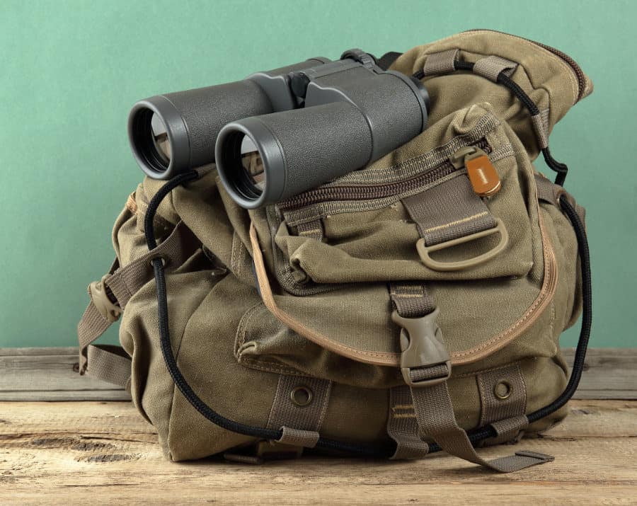Safari backpack and binoculars on hardwood floor