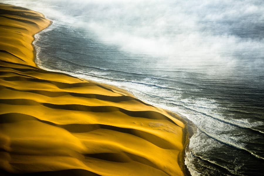 Skeleton Coast from above, featuring towering dunes soaring high against the Atlantic Ocean
