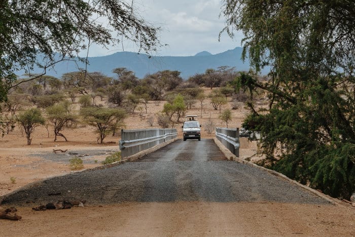 A safari minibus drives across a local bridge in Samburu