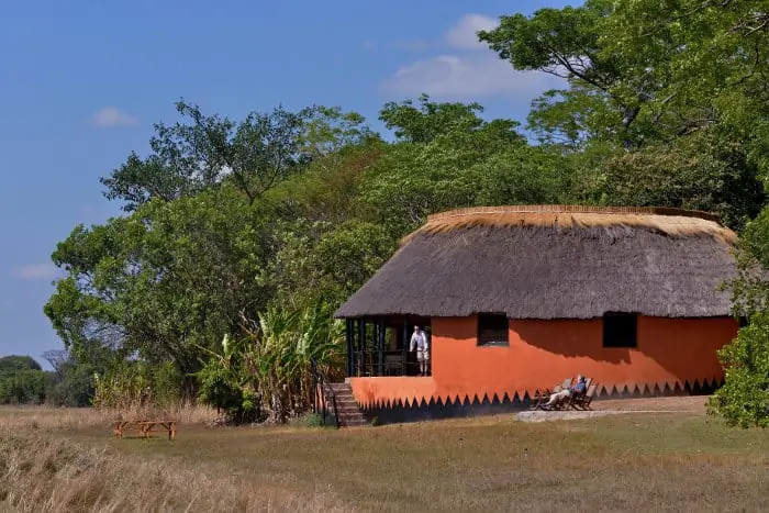 Outside view of a thatched-roof bungalow surrounded by nature
