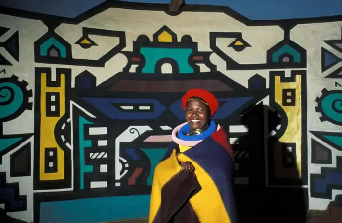 Ndebele woman in traditional clothing, against typical wall painting