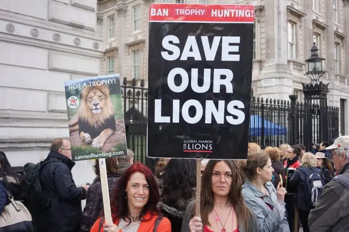 Two young women holding signs to save our lions