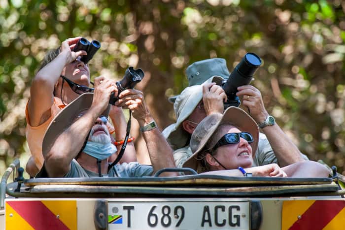 Tourists observing African animals with their cameras and binoculars
